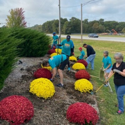 Volunteers planting mums at 20th & the Bypass Welcome sign.