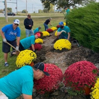 Volunteers planting mums at 20th & the Bypass Welcome sign.
